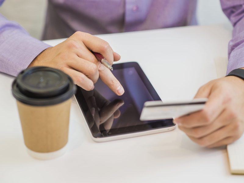 Man holding credit card and tablet on workplace background