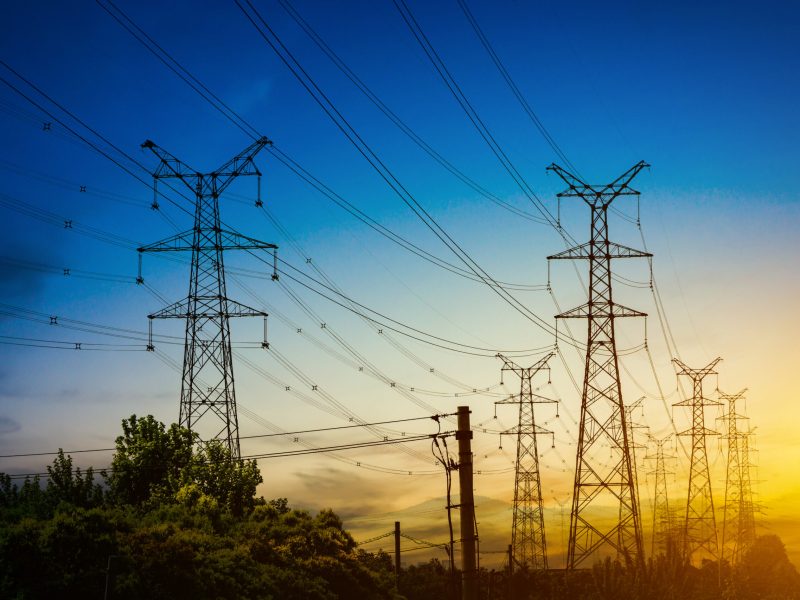 Sun setting behind the silhouette of electricity pylons