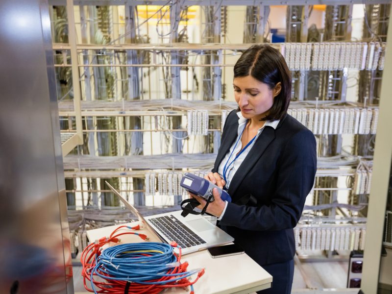 Beautiful technician using digital cable analyzer in server room